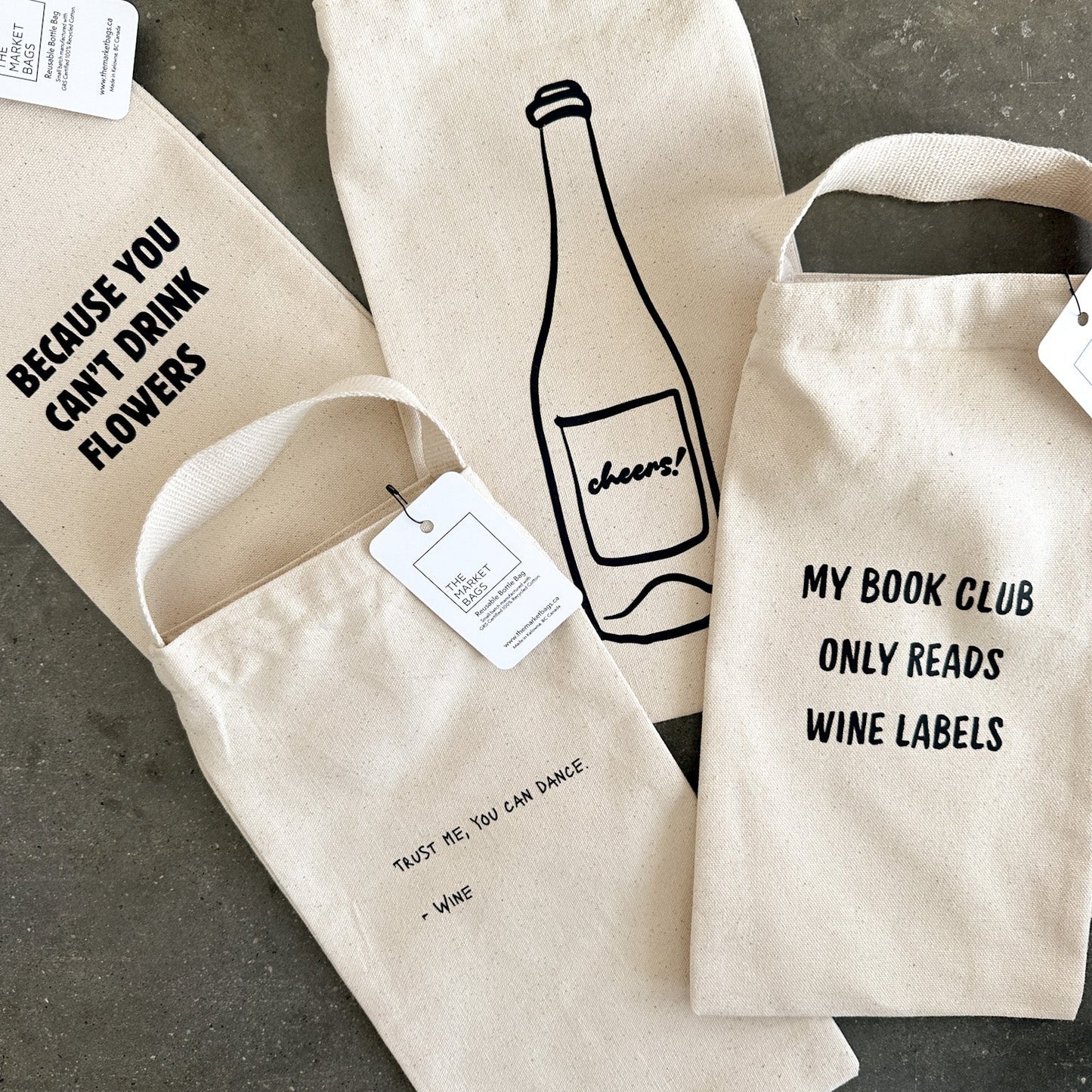Three wine bags with humorous text designs on a gray surface