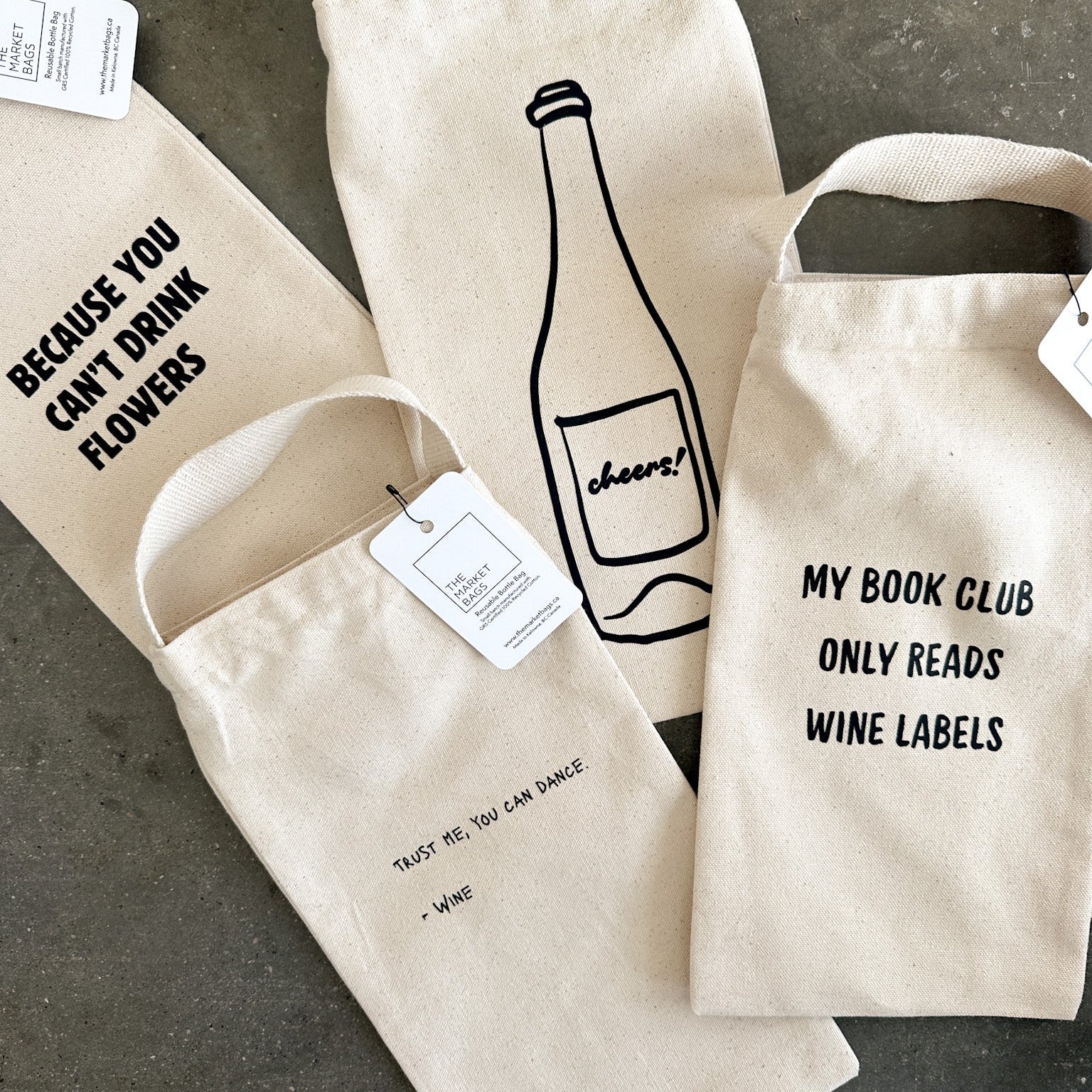 Three wine bags with humorous text designs on a gray surface