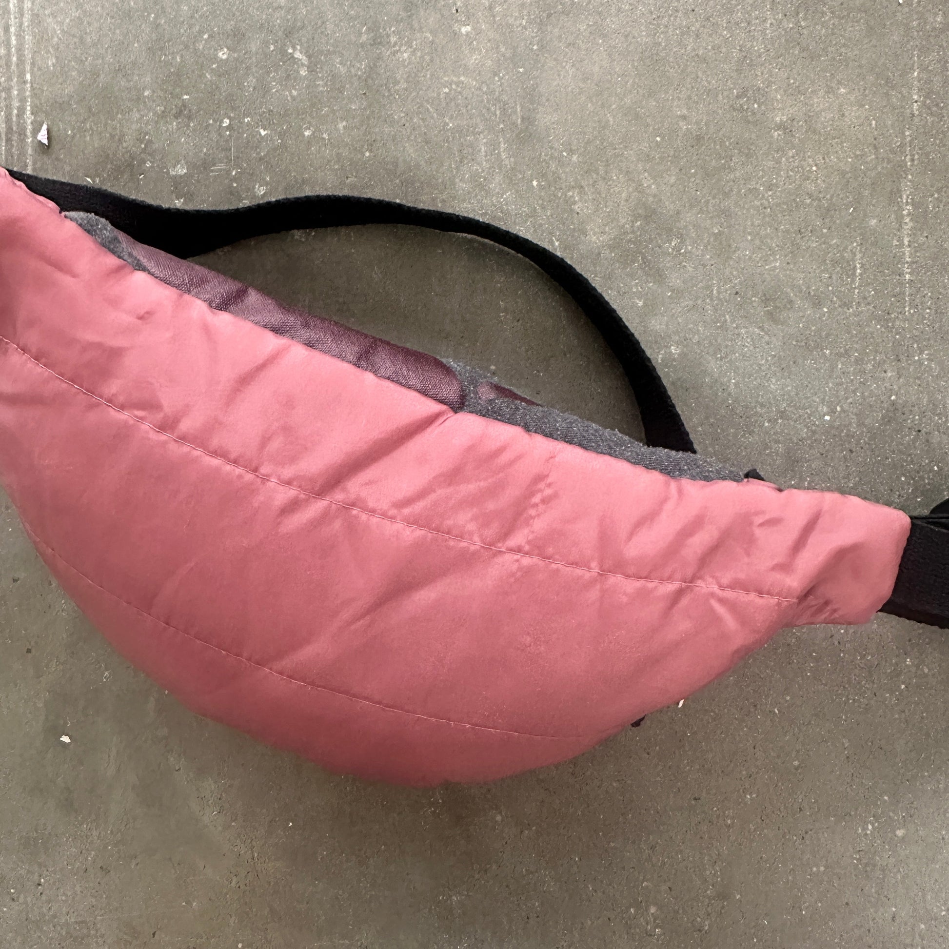 Pink quilted bag on a concrete floor